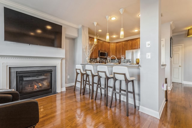 kitchen featuring kitchen peninsula, stainless steel appliances, a breakfast bar, tasteful backsplash, and ornamental molding