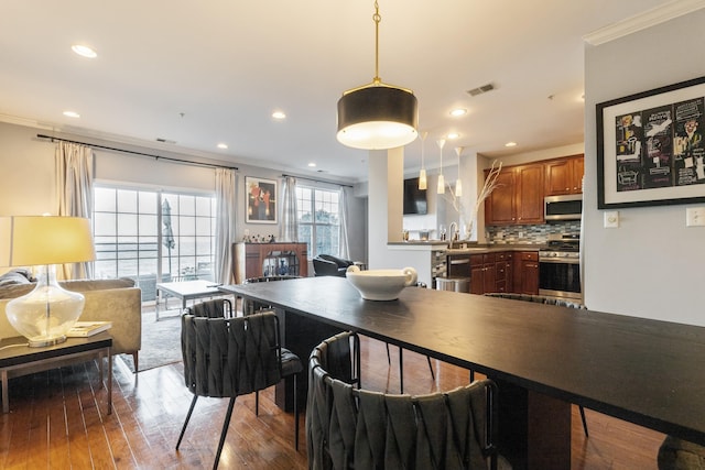 dining space with crown molding, wood-type flooring, and sink