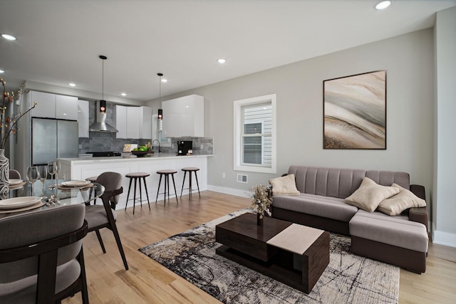 living room with light wood-style floors, recessed lighting, visible vents, and baseboards