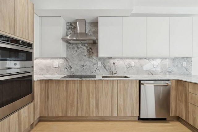 kitchen featuring stainless steel appliances, white cabinetry, wall chimney range hood, and backsplash