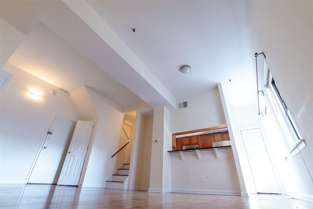 bonus room with a high ceiling and light wood-type flooring