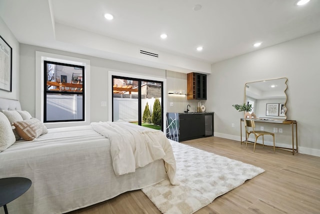 bedroom featuring sink, light wood-type flooring, and access to outside