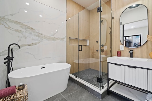 bathroom with tile walls, tile patterned flooring, plus walk in shower, and vanity