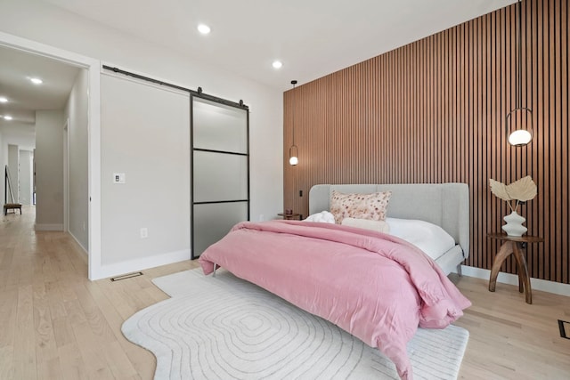 bedroom with light hardwood / wood-style floors and a barn door