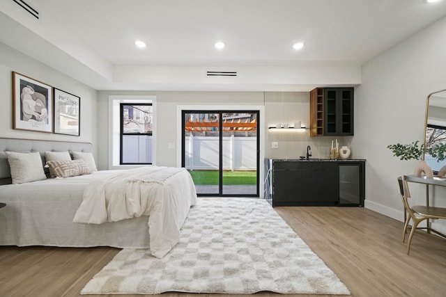 bedroom with access to outside, light hardwood / wood-style flooring, and sink