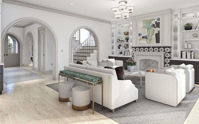 living area featuring ornamental molding, built in shelves, arched walkways, light wood-style floors, and an inviting chandelier