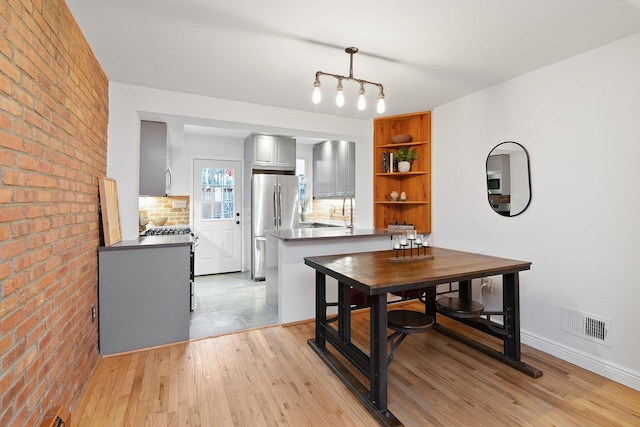 dining space featuring sink, brick wall, and light wood-type flooring