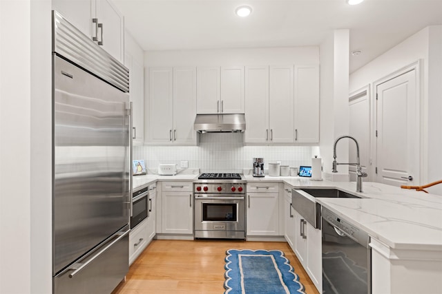 kitchen featuring tasteful backsplash, white cabinetry, sink, high end appliances, and light stone countertops