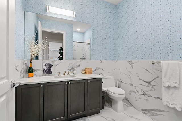 bathroom with vanity, tile walls, toilet, and a shower