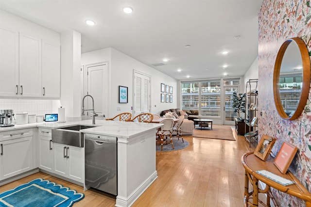 kitchen with sink, light hardwood / wood-style flooring, dishwasher, light stone countertops, and white cabinets