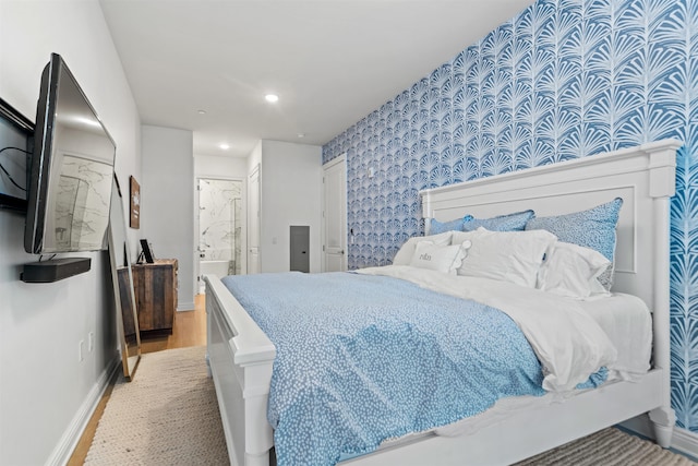 bedroom with ensuite bath and wood-type flooring