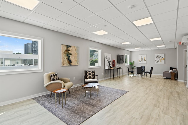 living area with light hardwood / wood-style floors, a drop ceiling, and a wealth of natural light