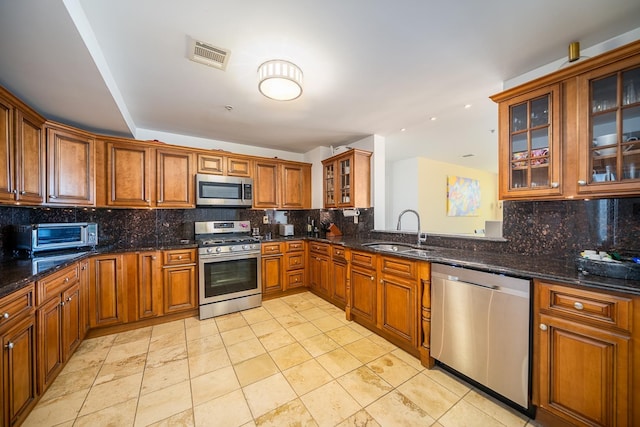 45 Broadway Unit 302, Jersey City, NJ 07306 - kitchen featuring appliances with stainless steel finishes, decorative backsplash, brown cabinets, glass insert cabinets, and dark stone countertops