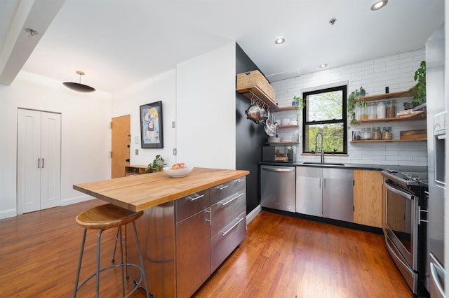kitchen featuring dark wood-style flooring, open shelves, a sink, butcher block countertops, and stainless steel appliances
