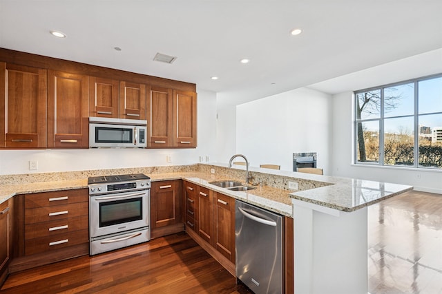 kitchen with a peninsula, dark wood-style floors, visible vents, appliances with stainless steel finishes, and a sink