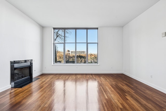 unfurnished living room with a high end fireplace, dark wood-style flooring, and baseboards