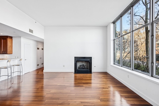 unfurnished living room featuring dark wood-type flooring, visible vents, and a wealth of natural light