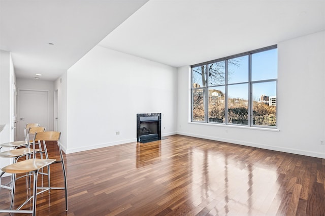 unfurnished living room featuring baseboards, wood finished floors, and a high end fireplace