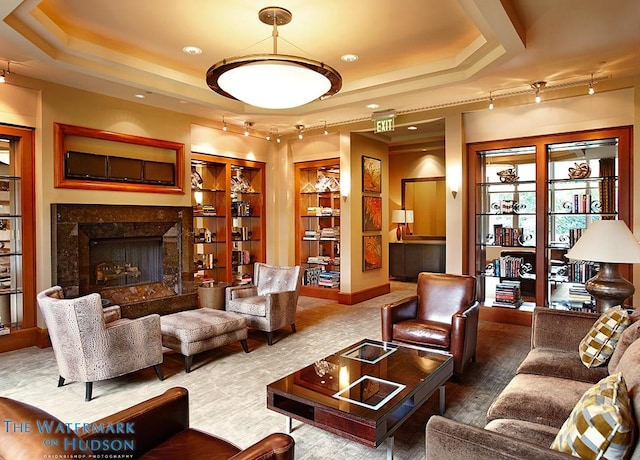 living room featuring a tray ceiling and a fireplace
