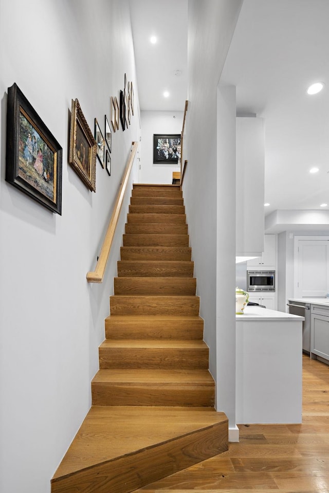 stairway featuring wood finished floors and recessed lighting