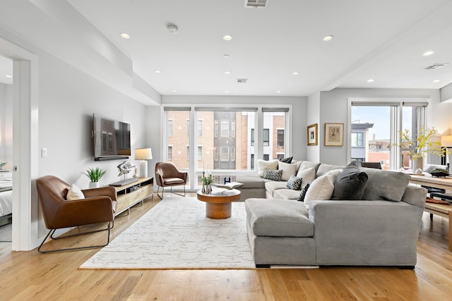 living area with visible vents, light wood-type flooring, and recessed lighting