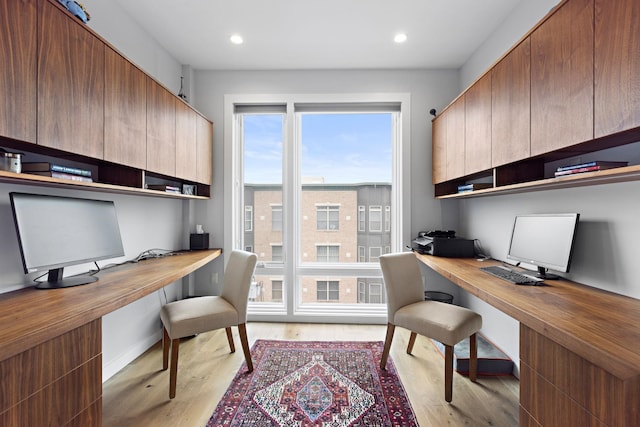 office featuring baseboards, recessed lighting, light wood-style flooring, and built in desk