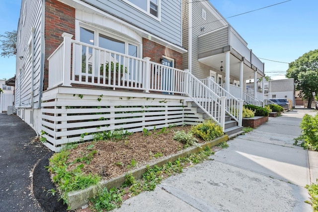 80 E 24th St, Bayonne, NJ 07002 - view of property exterior featuring covered porch, brick siding, and central AC unit