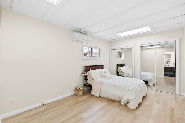 80 E 24th St, Bayonne, NJ 07002 - bedroom with a wall mounted AC, two closets, light wood-style floors, and baseboards