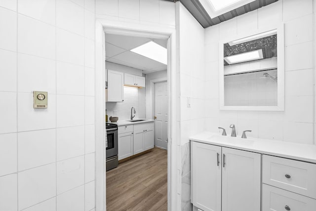 80 E 24th St, Bayonne, NJ 07002 - full bathroom featuring vanity, wood finished floors, tile walls, and decorative backsplash