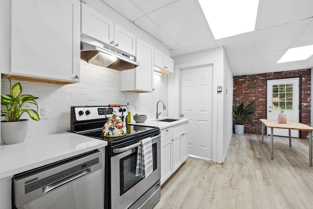 80 E 24th St, Bayonne, NJ 07002 - kitchen with stainless steel appliances, under cabinet range hood, a sink, a paneled ceiling, and light wood-style floors