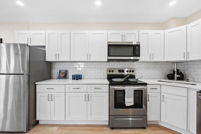 80 E 24th St, Bayonne, NJ 07002 - kitchen with appliances with stainless steel finishes, a sink, light countertops, white cabinetry, and recessed lighting
