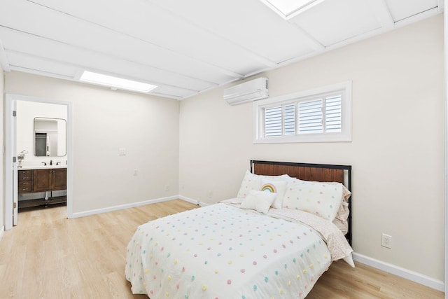 80 E 24th St, Bayonne, NJ 07002 - bedroom featuring an AC wall unit, wood finished floors, baseboards, connected bathroom, and a sink