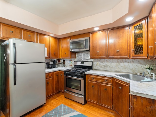 kitchen with light countertops, brown cabinets, appliances with stainless steel finishes, and a sink