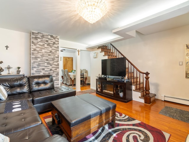 living area with wood finished floors, baseboards, stairs, a baseboard heating unit, and a chandelier