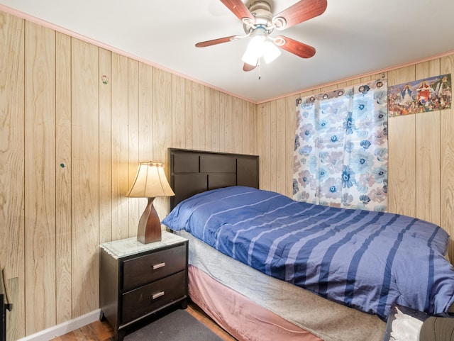 bedroom with baseboards, wood walls, and a ceiling fan