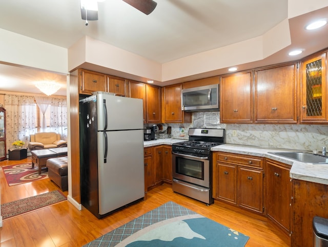 kitchen featuring light wood-style flooring, brown cabinetry, appliances with stainless steel finishes, and a sink