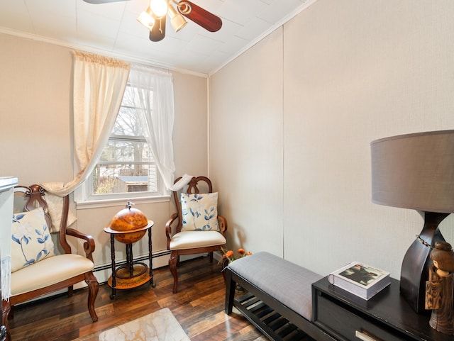 sitting room with ceiling fan, a baseboard radiator, wood finished floors, and crown molding