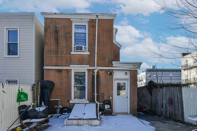 snow covered property featuring brick siding and fence