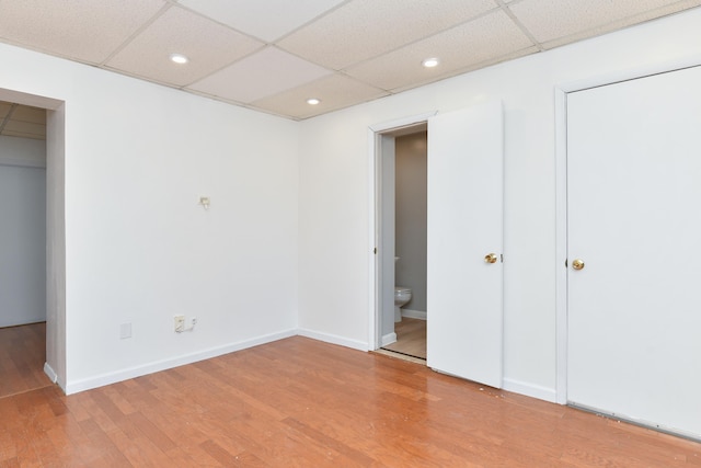 unfurnished bedroom featuring light wood-type flooring, a paneled ceiling, baseboards, and recessed lighting