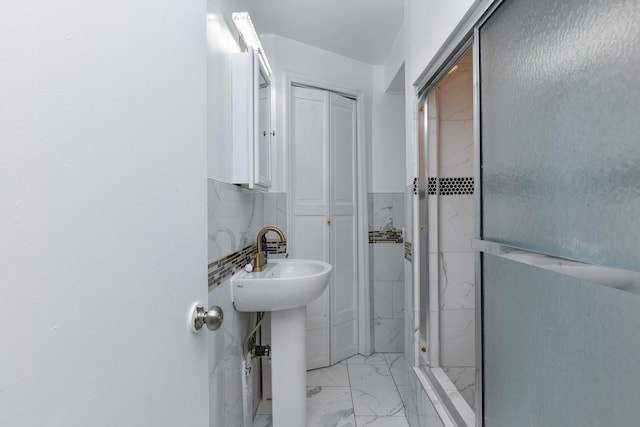 bathroom featuring a stall shower, a closet, a sink, and marble finish floor