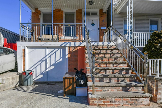 view of exterior entry featuring a garage, covered porch, and brick siding