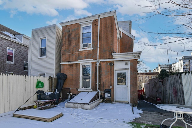 snow covered back of property with a fenced backyard and brick siding