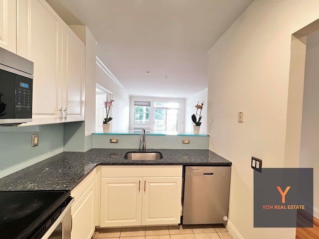 1100 River Rd, Edgewater, NJ 07020 - kitchen featuring appliances with stainless steel finishes, white cabinets, dark stone counters, a peninsula, and light tile patterned flooring