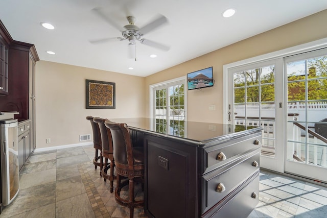 kitchen featuring dark countertops, a kitchen bar, a ceiling fan, and recessed lighting