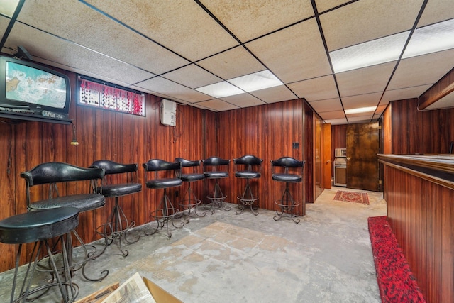 bar featuring a dry bar, wood walls, and unfinished concrete floors
