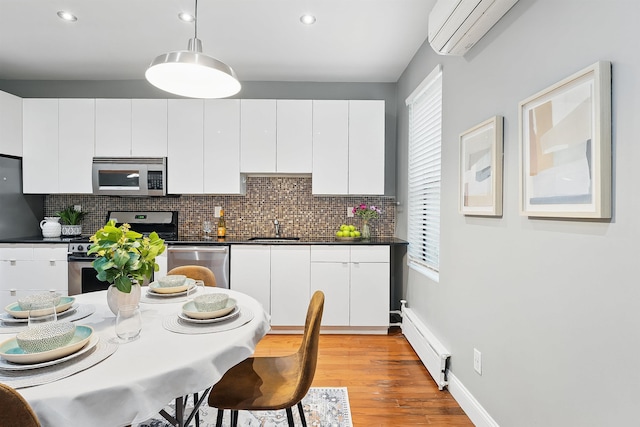29 51st St Unit A2, Weehawken, NJ 07086 - kitchen featuring appliances with stainless steel finishes, a baseboard radiator, a wall mounted air conditioner, dark countertops, and a sink