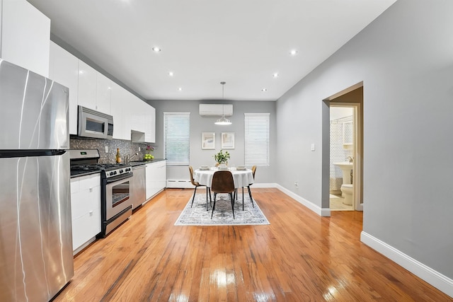 29 51st St Unit A2, Weehawken, NJ 07086 - kitchen with stainless steel appliances, a wall mounted AC, white cabinetry, light wood-style flooring, and modern cabinets