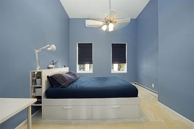 carpeted bedroom with a baseboard heating unit, an AC wall unit, and ceiling fan