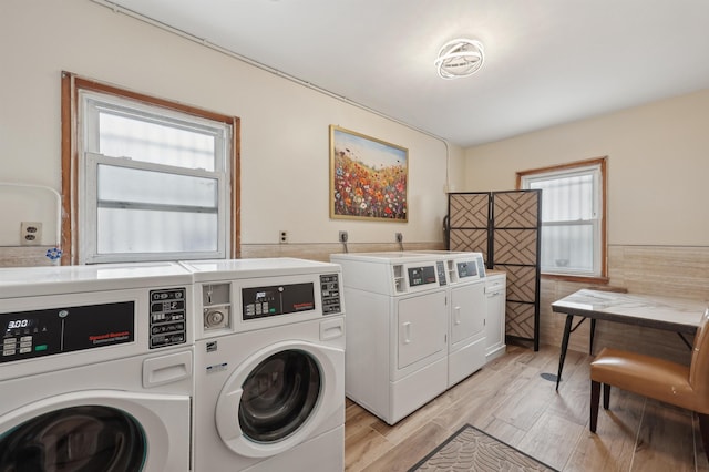 clothes washing area featuring tile walls, independent washer and dryer, and light wood-type flooring