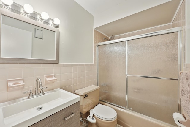 full bathroom featuring tile walls, shower / bath combination with glass door, vanity, and toilet